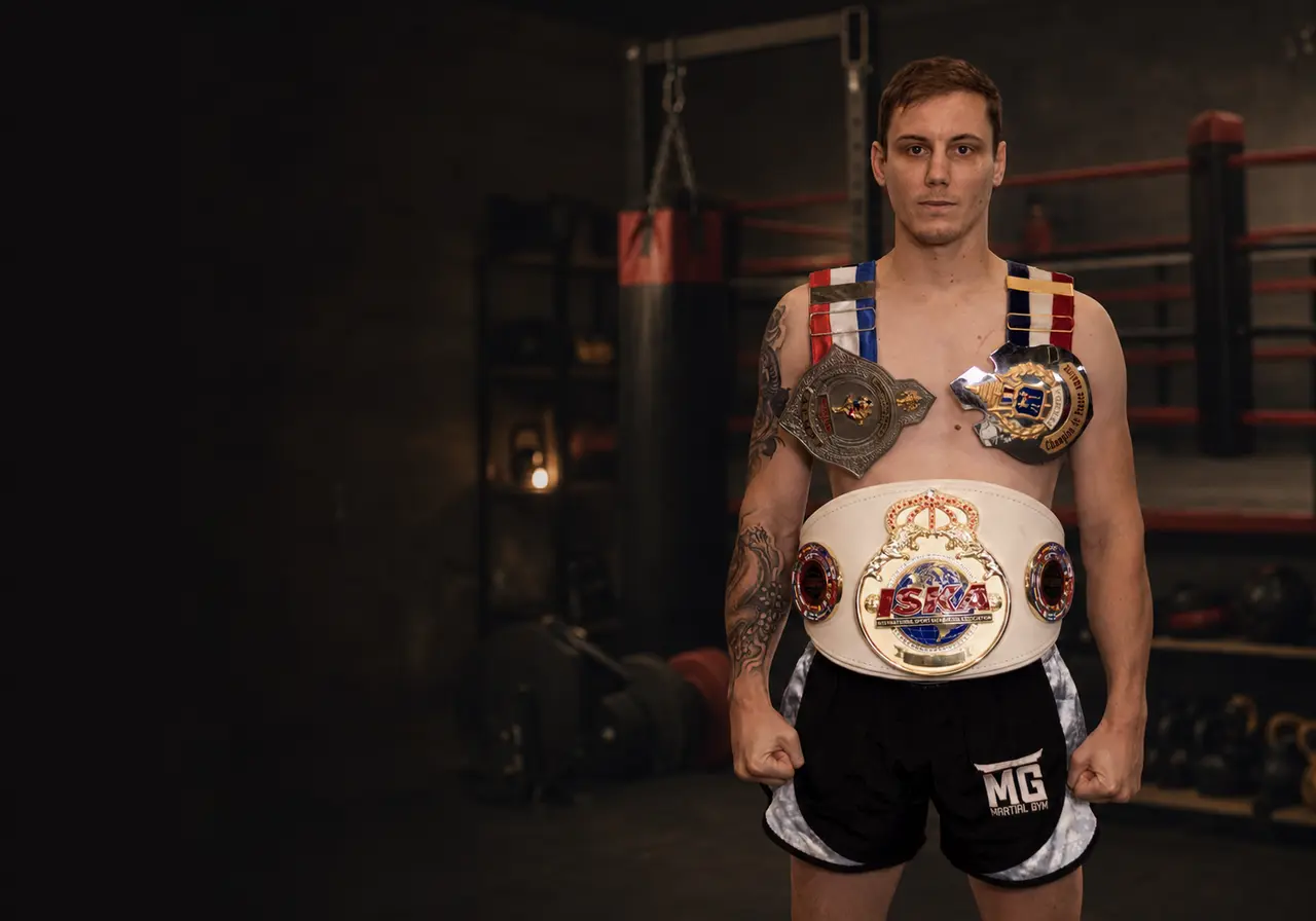Antonin Marconi avec ses ceintures de champion dans une salle de Muay Thai et de préparation physique